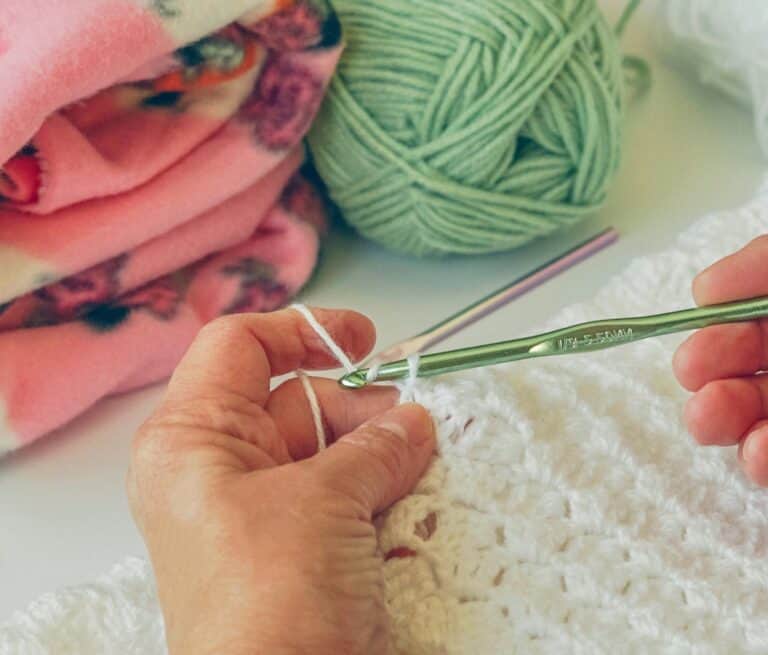 Handen haken een wit babydekentje als persoonlijk cadeau