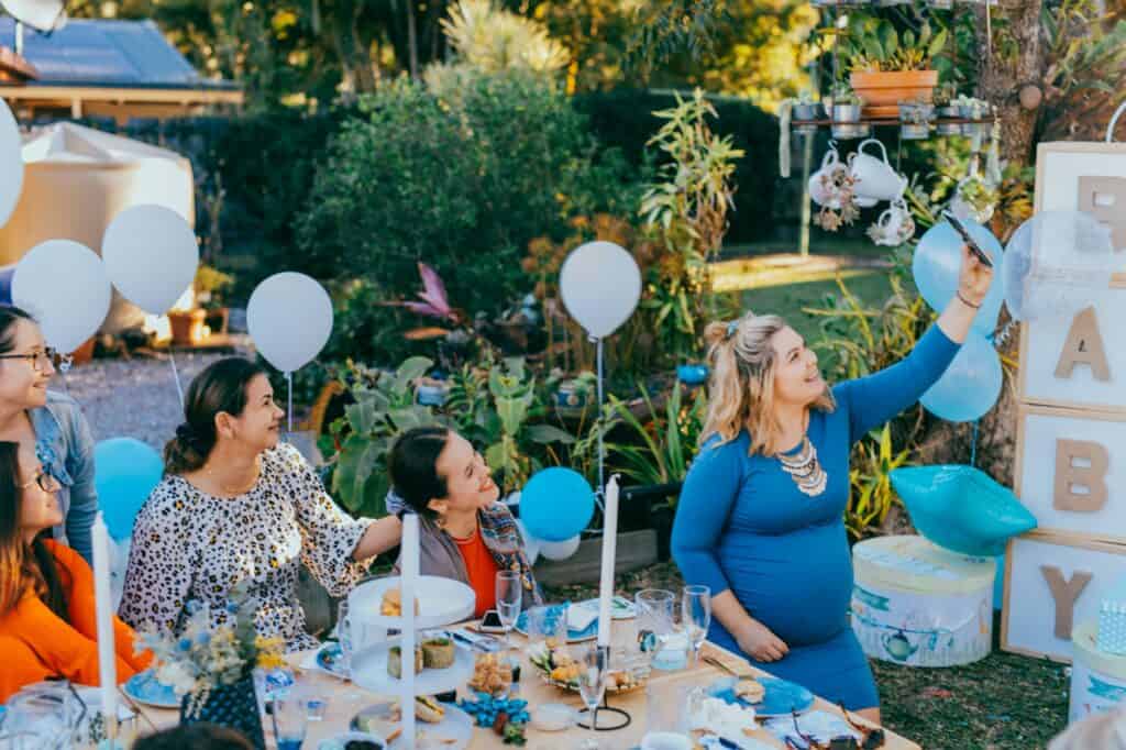 Vriendinnen maken samen een selfie tijdens een babyshower in de tuin
