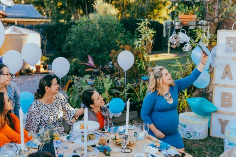 Vriendinnen maken samen een selfie tijdens een babyshower in de tuin
