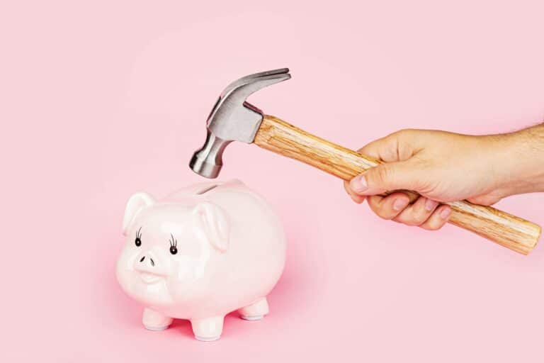 Hand broke piggy bank on pink background
