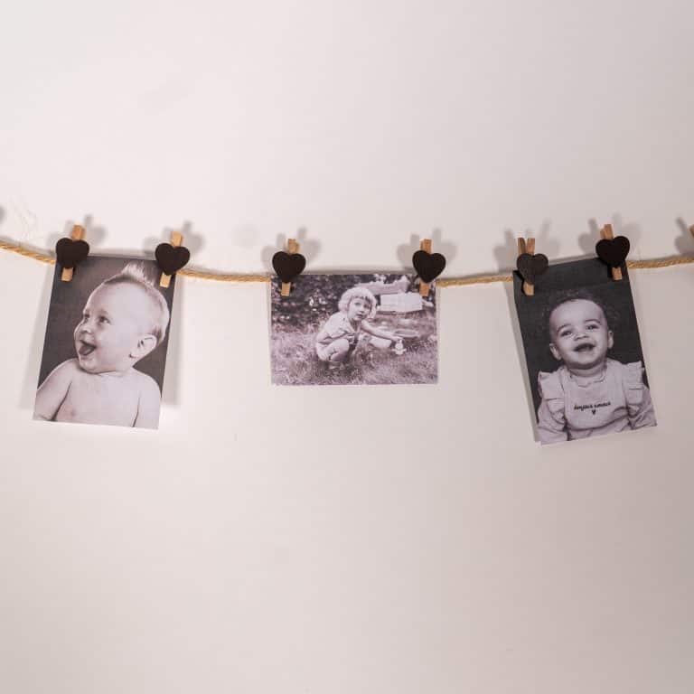 Babyfoto’s aan een lijn met hartjesknijpers voor het babyshowerspel raad de babyfoto