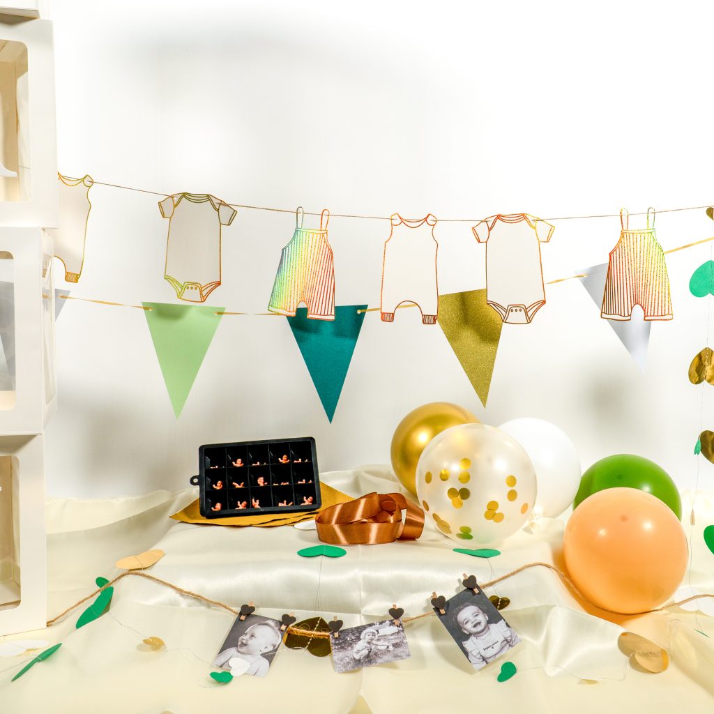 Babyshowerdecoratie met groene vlaggetjes, gouden romperslinger en ballonnen